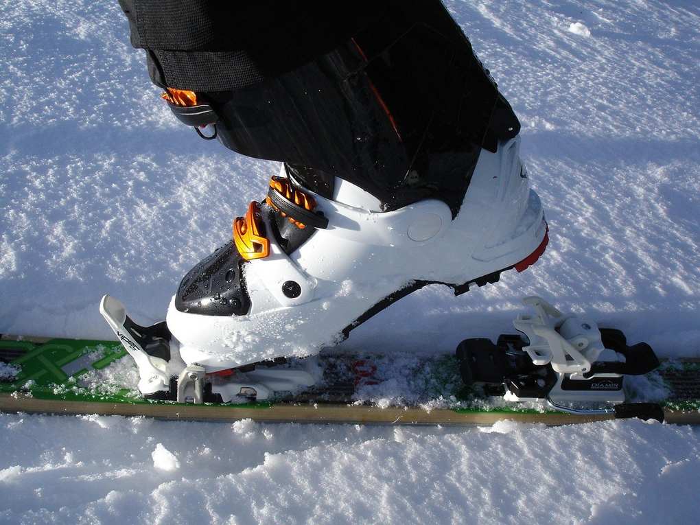 Botte de ski blanche et noire fixée sur une planche, sur fond de neige Botte de ski blanche et noire fixée sur une planche, sur fond de neige