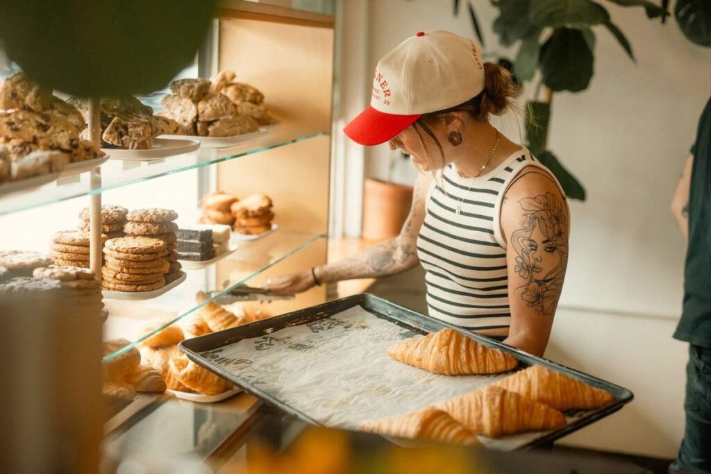 Femme devant vitrine de pâtisseries, tenant plateau de croissants