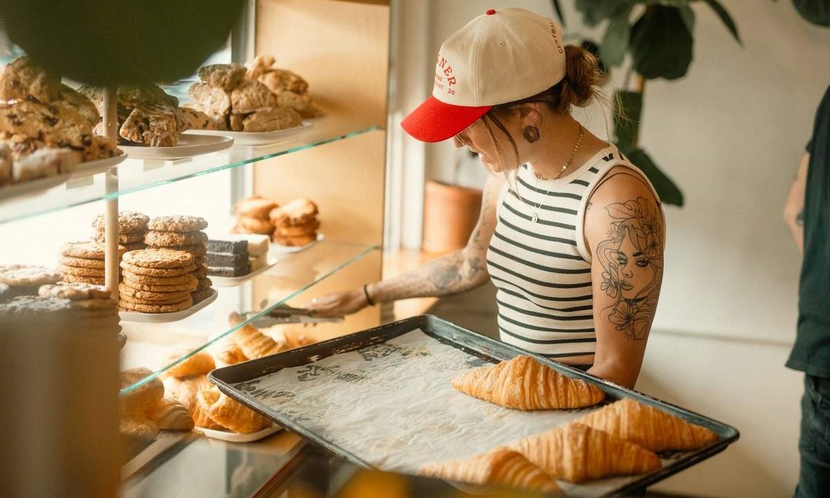 Femme devant vitrine de pâtisseries, tenant plateau de croissants