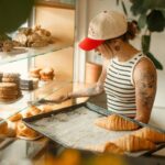 Femme devant vitrine de pâtisseries, tenant plateau de croissants