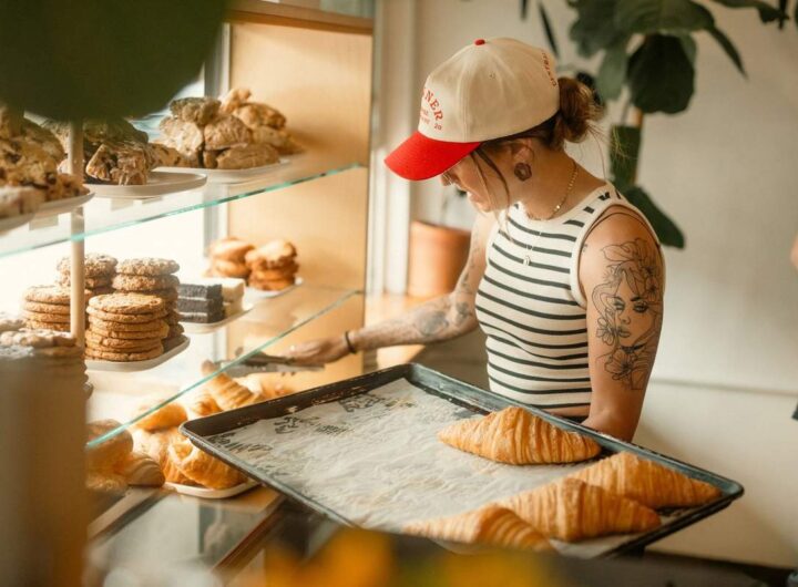 Femme devant vitrine de pâtisseries, tenant plateau de croissants